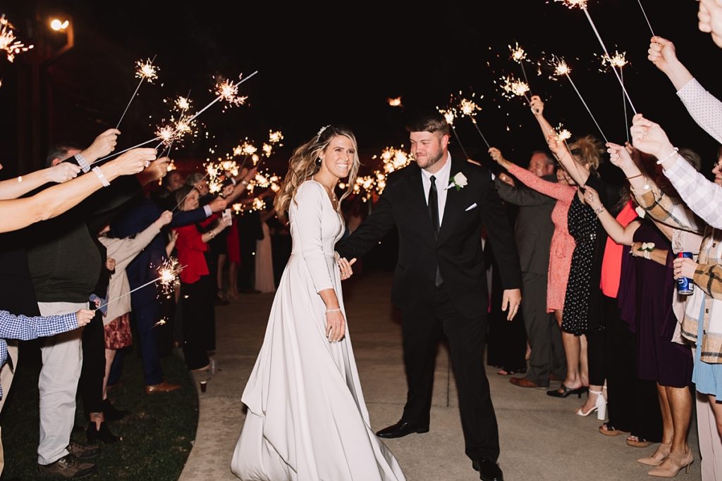 Groom walking with bride during their sparkler exit