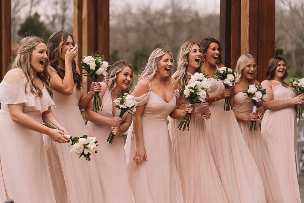 First look with bridesmaids as they smile and express joy at seeing the bride on her wedding day
