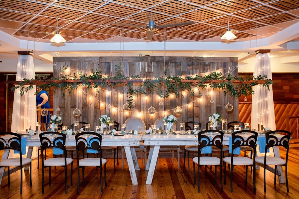 Head table inside of Legacy Farms reception venue showing hanging greenery overhead