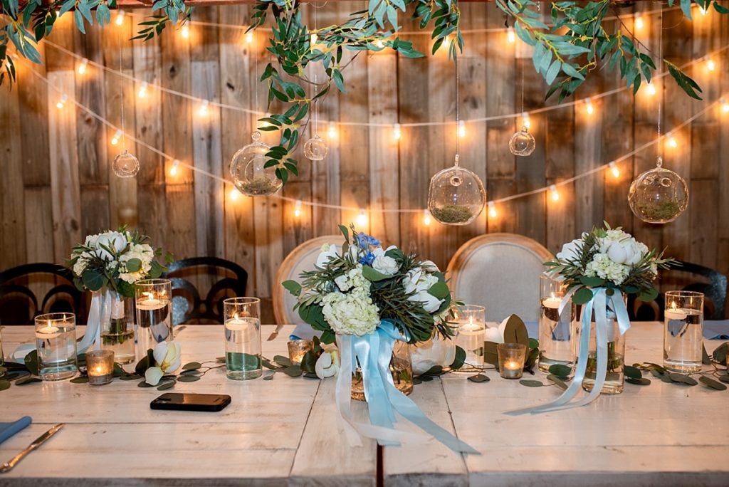 Headtable with hanging round bud vases, greenery and white wash farm tables