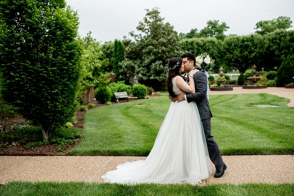 Couple sharing a kiss in the courtyard at Legacy Farms during their first look photos