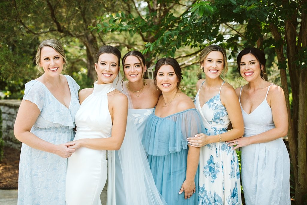 Bride in a halter dress with bridesmaids wearing dresses in shades of light blue